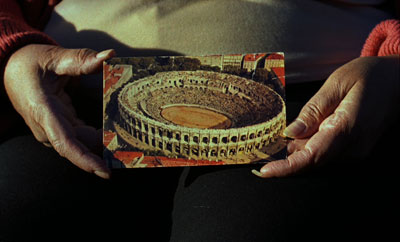 Mains tenant une photo du Colysée, photo de l'installation de Sara Millot intitulée Images du monde