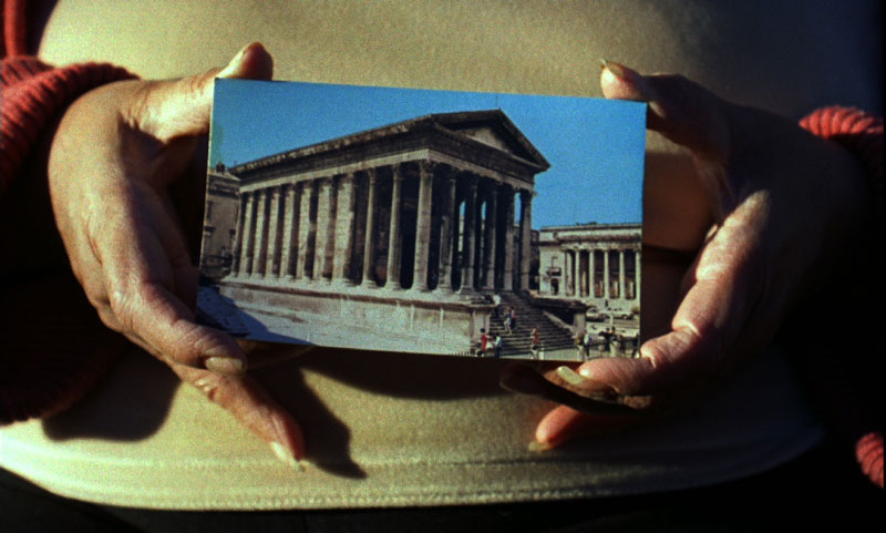 Mains tenant une photo du Colysée, photo de l'installation de Sara Millot intitulée Images du monde
